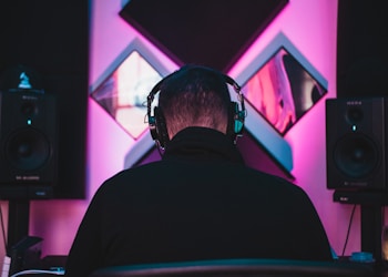 man wearing black headphones near two PA speakers