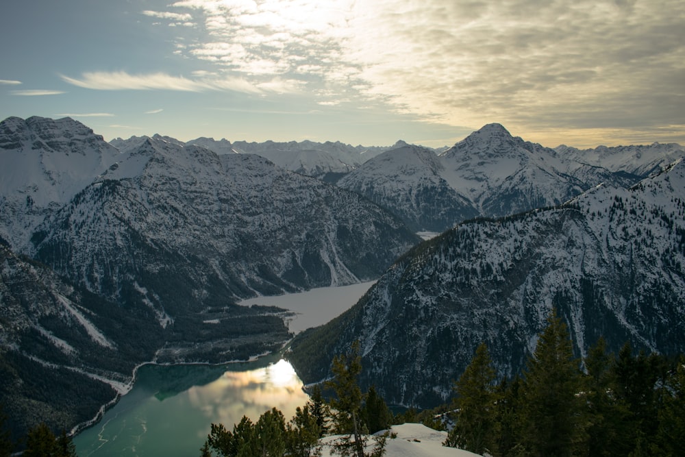 body of water beside snowy mountains