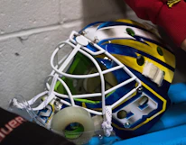 Close-up of hockey gloves and pads inside a sleek ozone sanitizing chamber glowing with electric blue light.