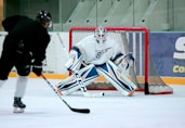man taking aim for goal on hockey goalie
