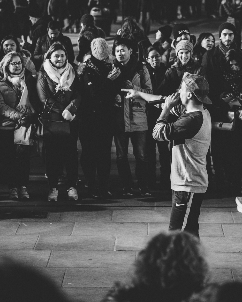 gray scale photo of man performing in front of people on street