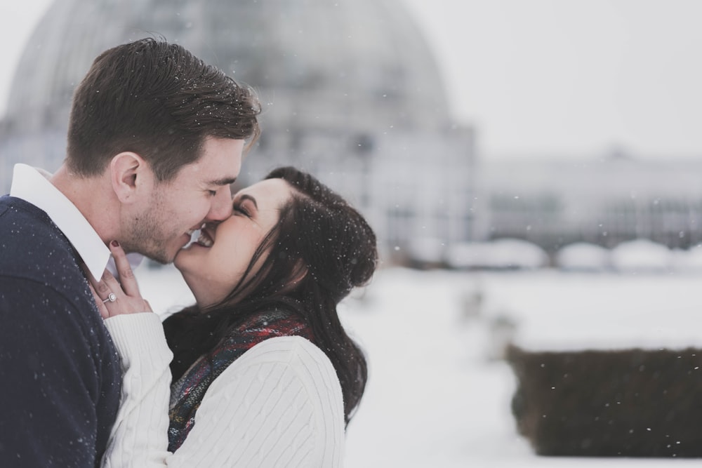 Homem e mulher se beijando no tempo de neve