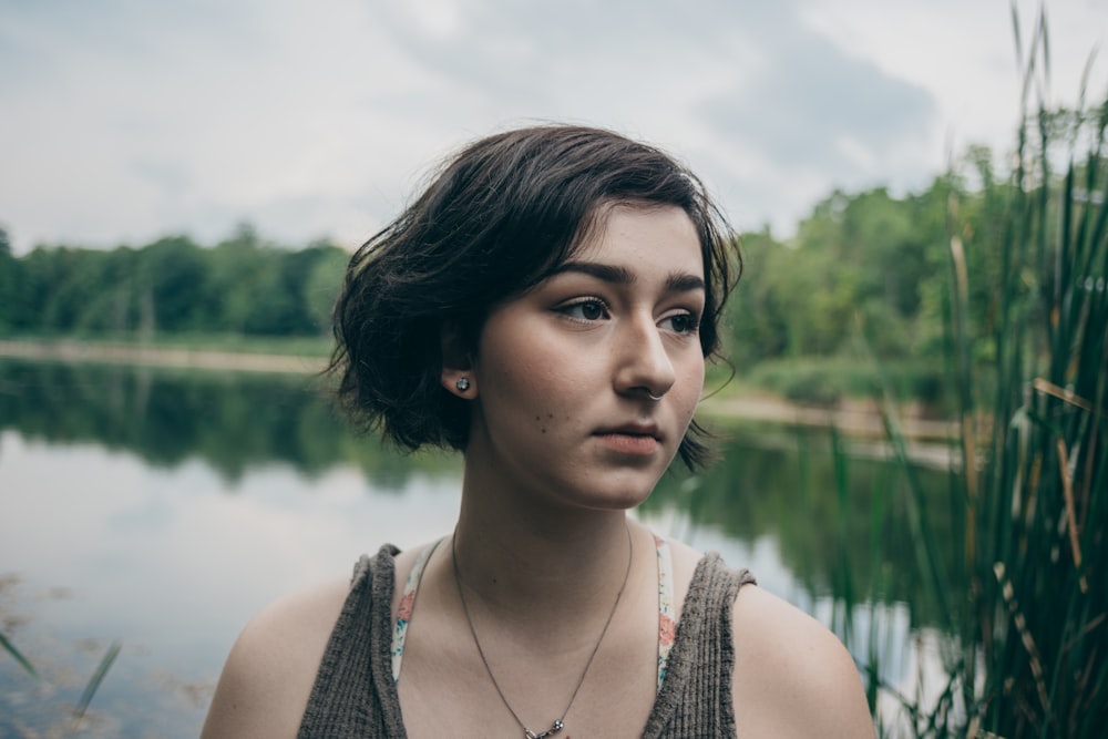 woman in gray tank top with body of water background