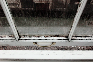 Close-up of a hand trying to slide a stuck window with visible dust on the tracks.
