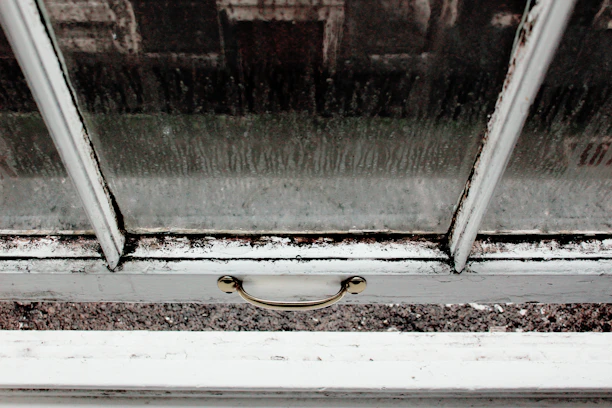 Close-up of a hand trying to slide a stuck window with visible dust on the tracks.