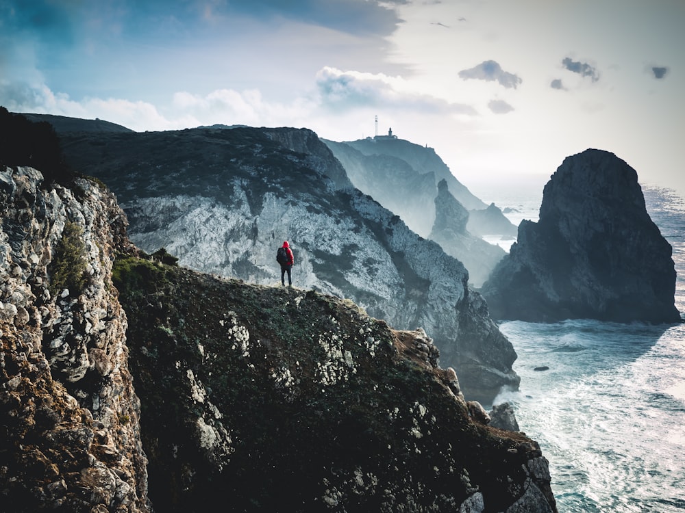 person on top of mountain near body of water