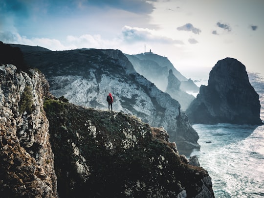 person on top of mountain near body of water in Cabo da Roca Portugal