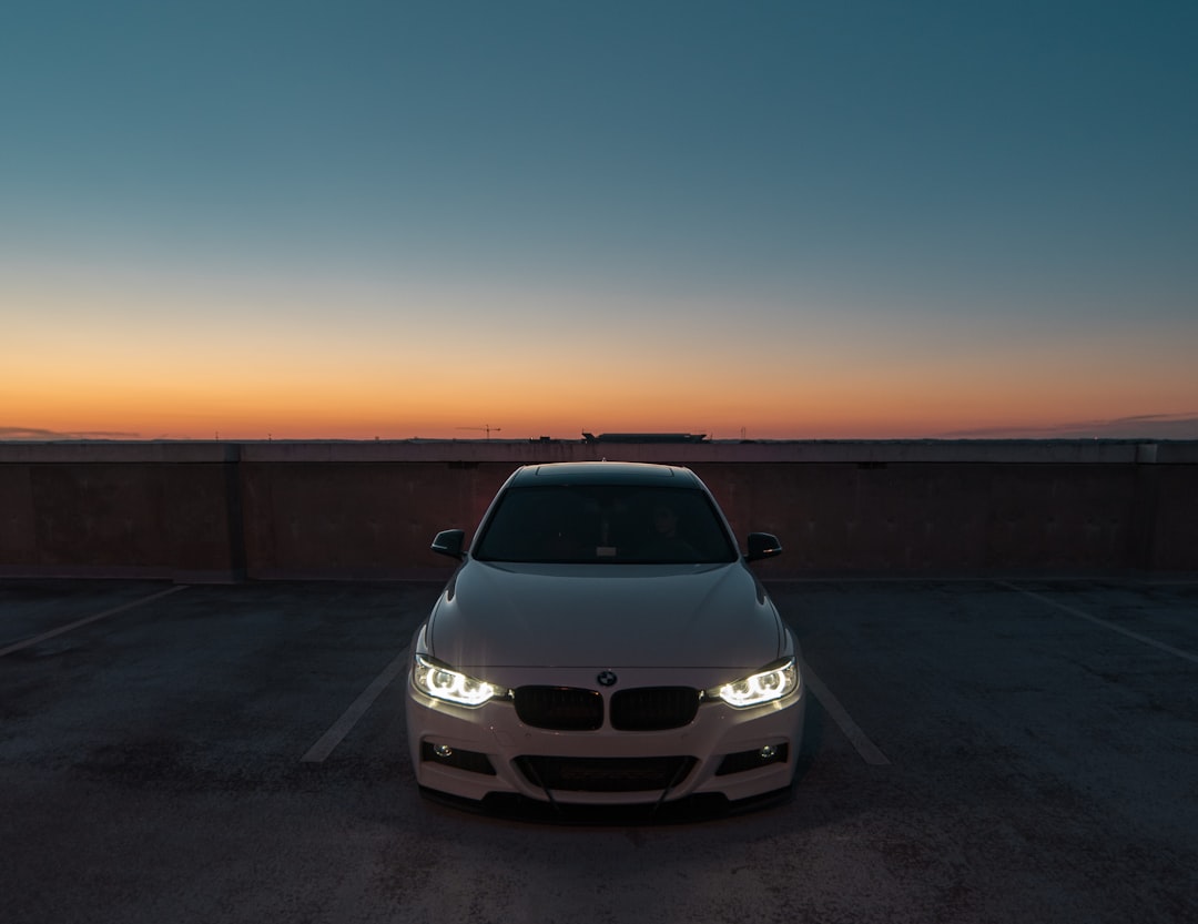 white BMW car near the wall parked