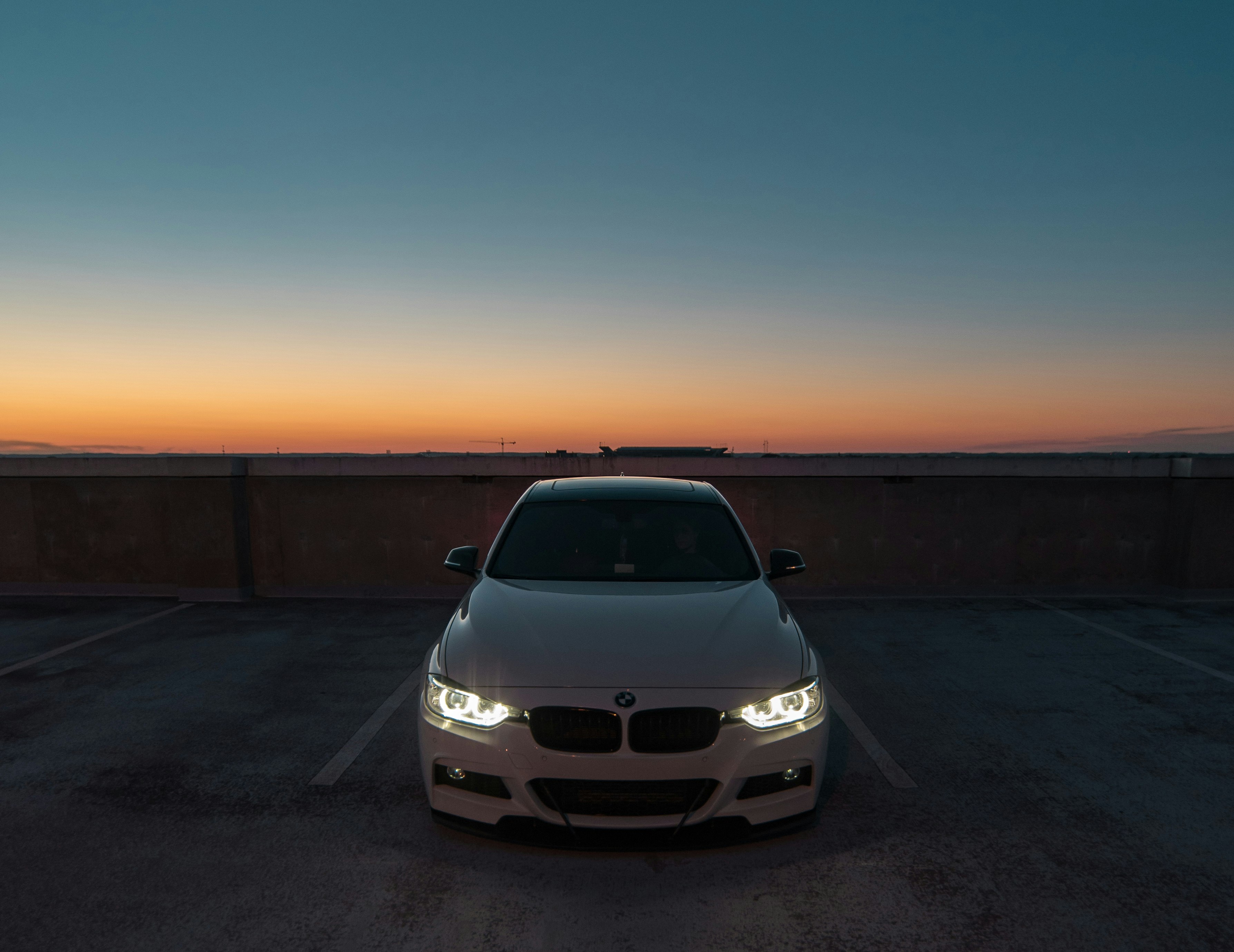 white BMW car near the wall parked