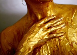 person coated with gold colored liquid posing