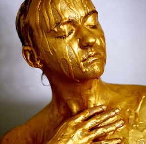 person coated with gold colored liquid posing