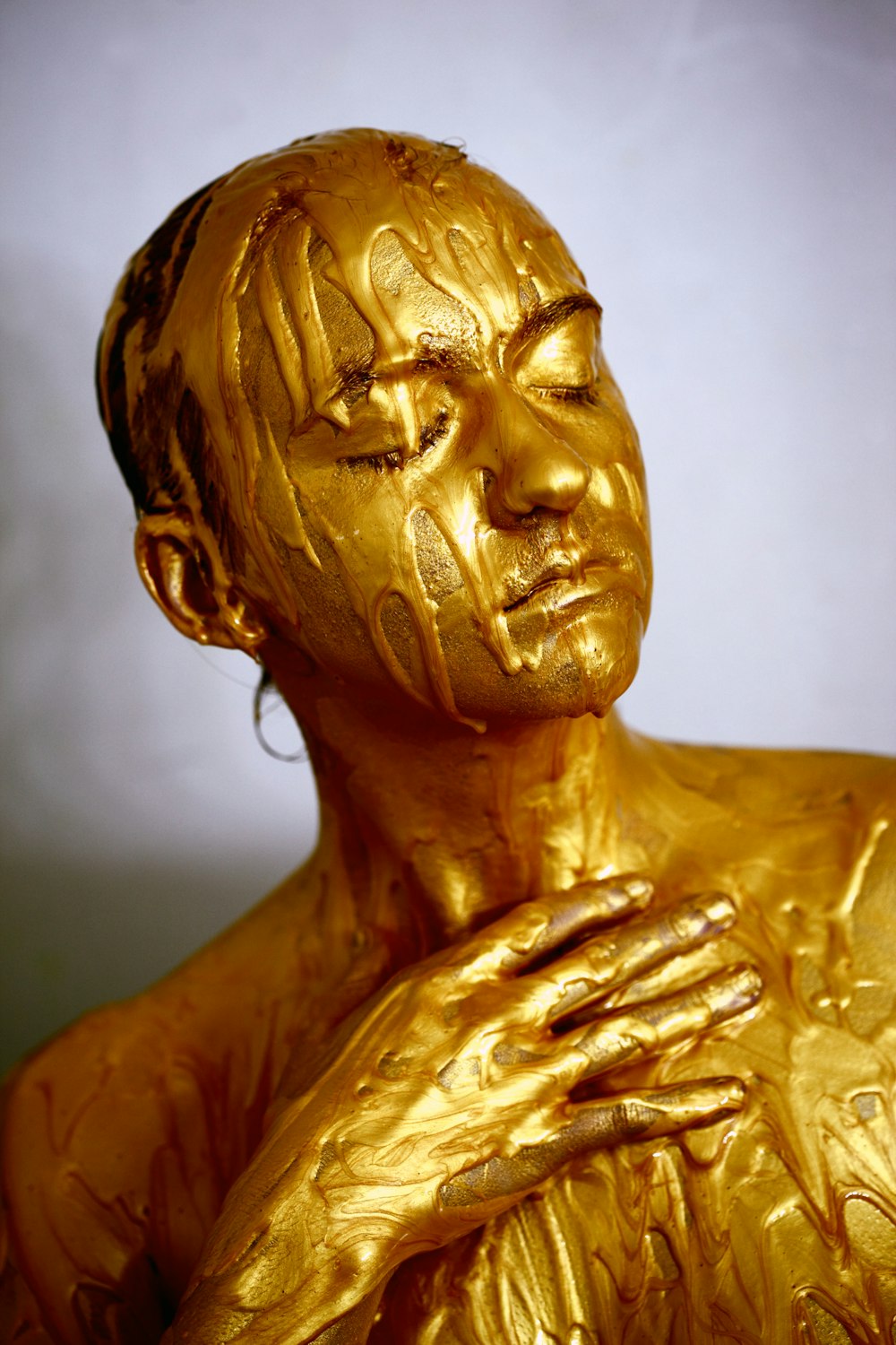 person coated with gold colored liquid posing