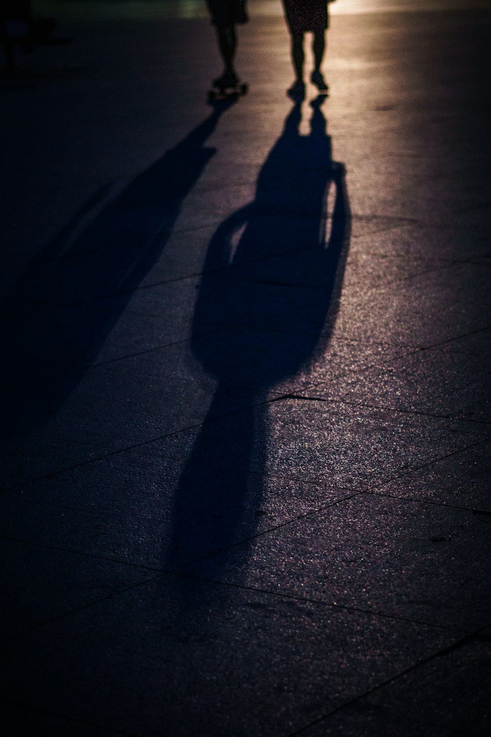 two people walking with shadows on road