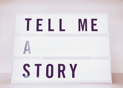 A lightbox with bold black letters spelling out the phrase 'TELL ME A STORY' in an orderly manner with each word on a separate line.