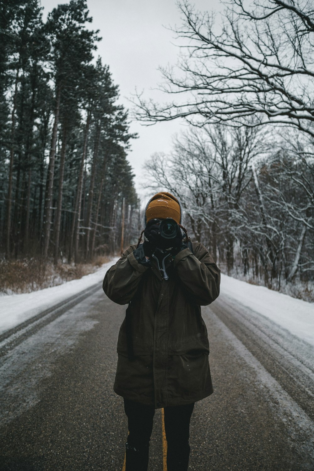 person in brown jacket holding camera