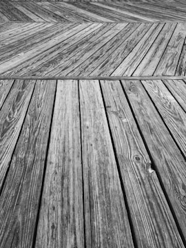 Wooden planks arranged in a chevron pattern, with visible grain and texture, create a geometric and abstract composition.