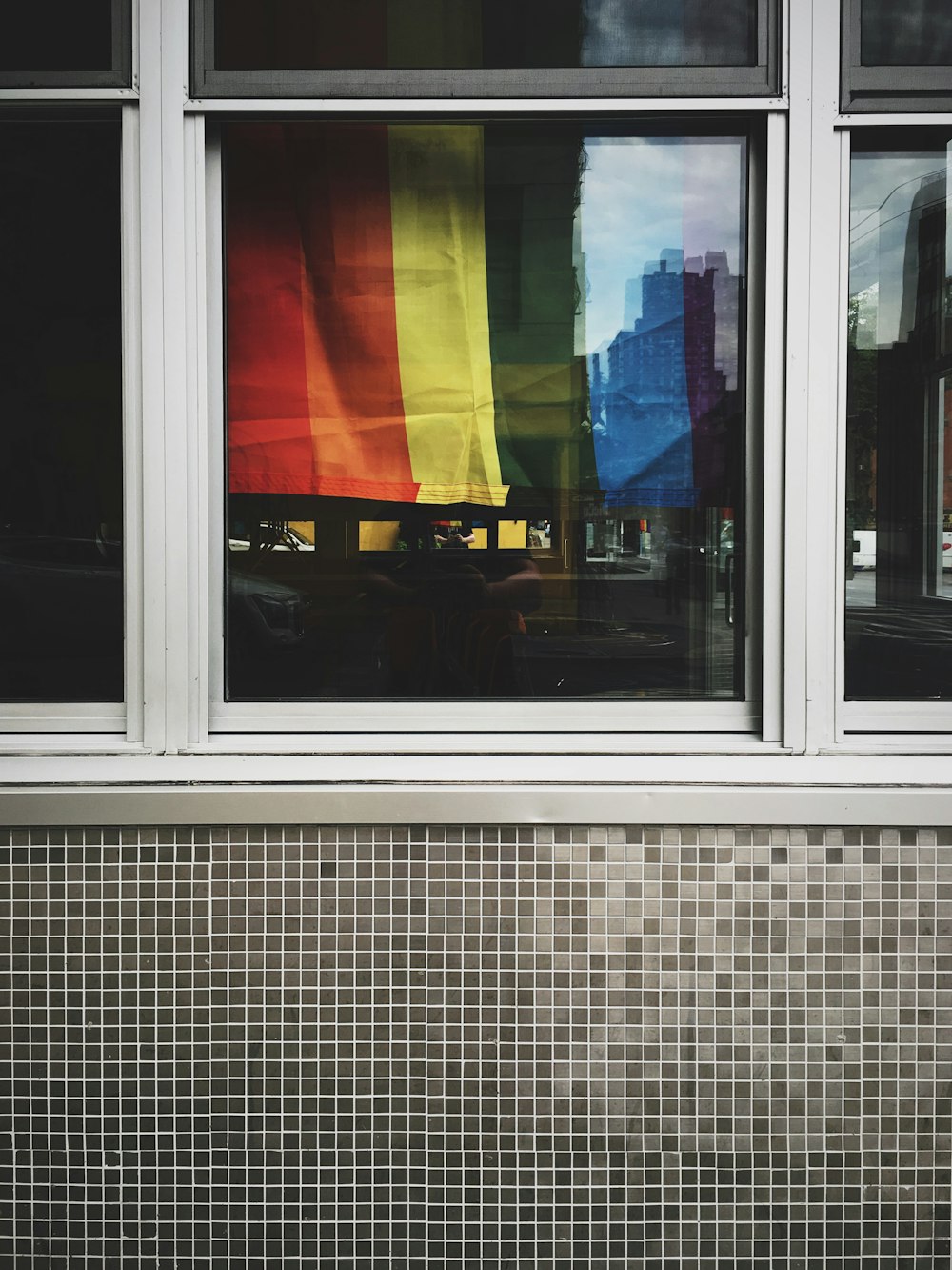 a rainbow flag is reflected in a window