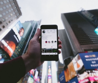 high angle photo of person holding turned on smartphone with tall buildings background