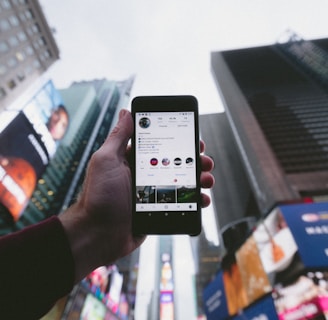 high angle photo of person holding turned on smartphone with tall buildings background