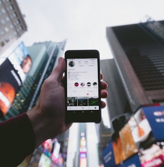 high angle photo of person holding turned on smartphone with tall buildings background