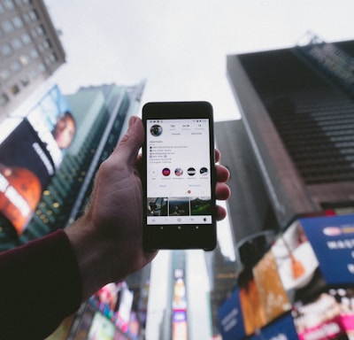 high angle photo of person holding turned on smartphone with tall buildings background