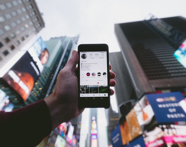 high angle photo of person holding turned on smartphone with tall buildings background