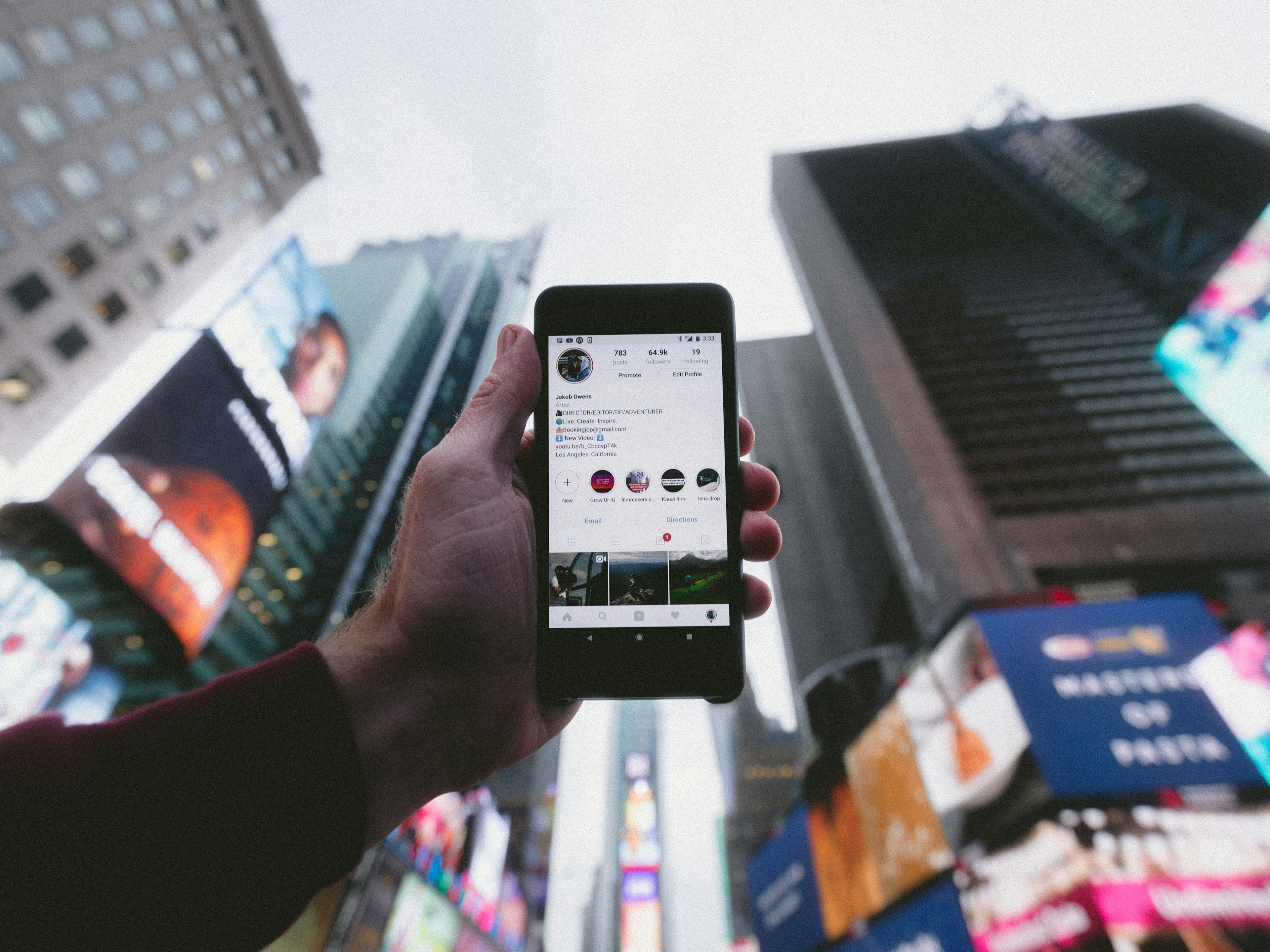 high angle photo of person holding turned on smartphone with tall buildings background