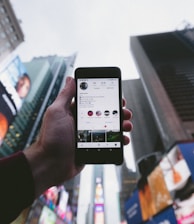 high angle photo of person holding turned on smartphone with tall buildings background