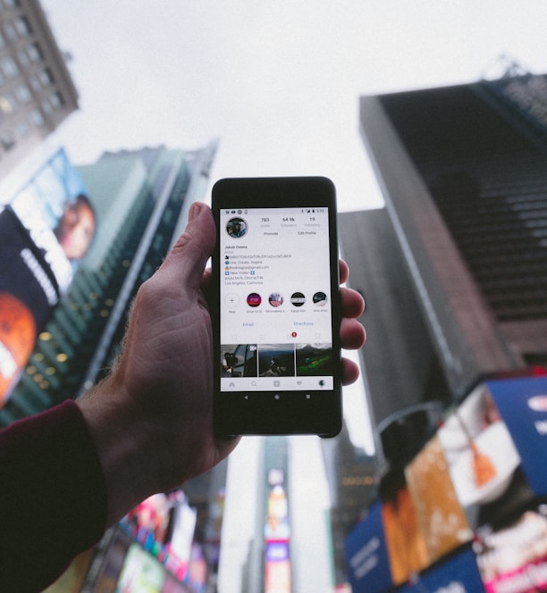 high angle photo of person holding turned on smartphone with tall buildings background