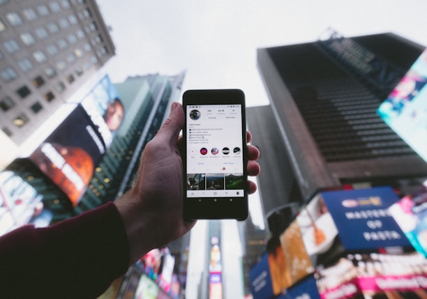 high angle photo of person holding turned on smartphone with tall buildings background