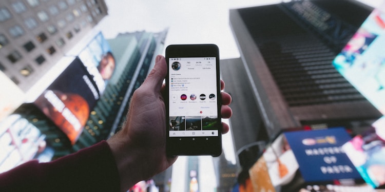 high angle photo of person holding turned on smartphone with tall buildings background