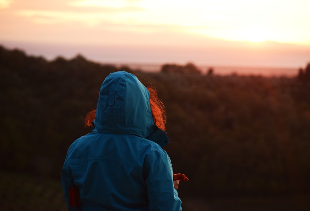 woman in blue hoodie standing on brown field during daytime