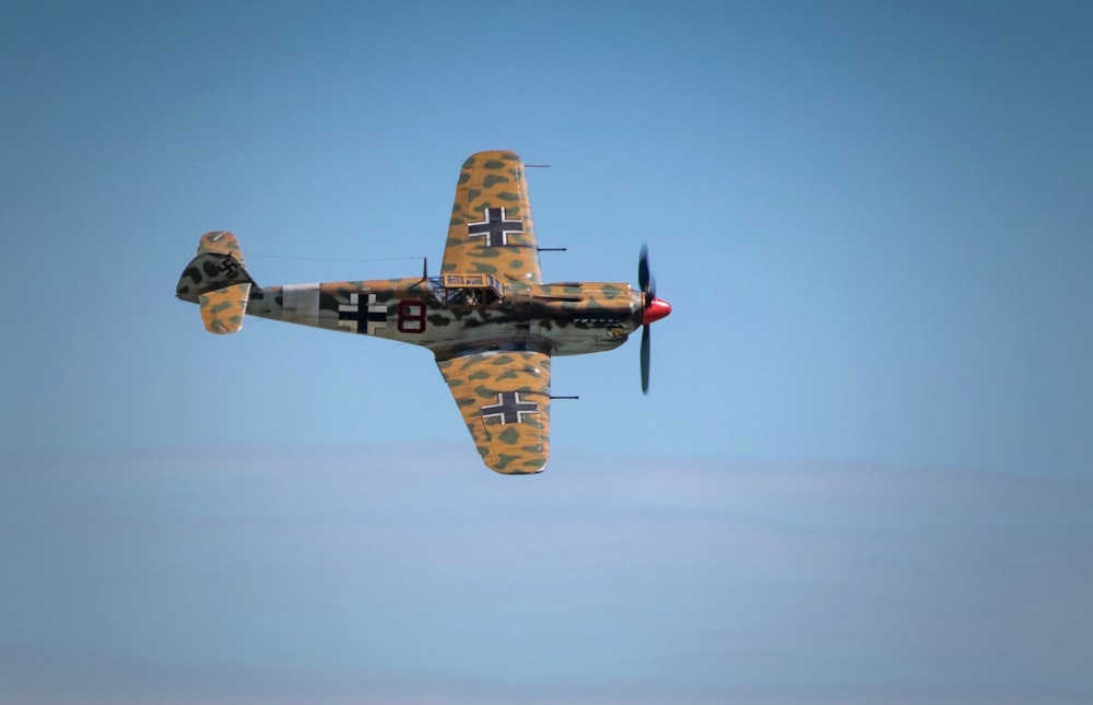 brown fighter plane above clouds