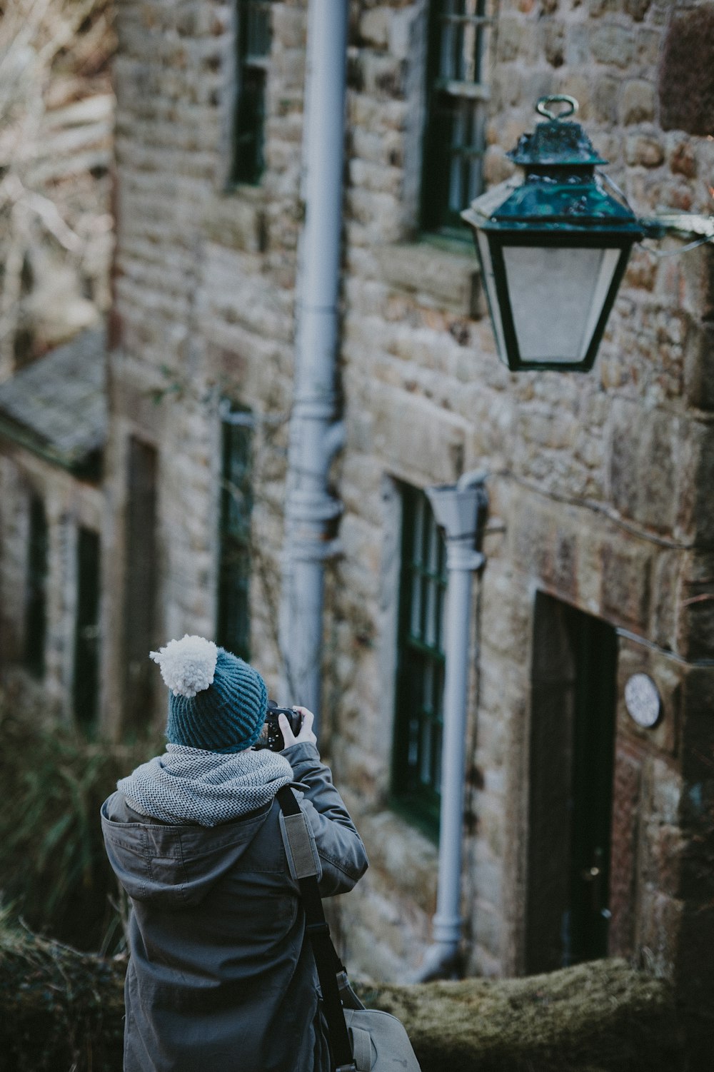 person in blue bobble cap taking photo with camera