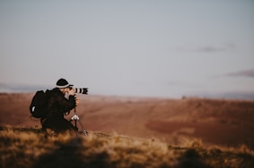 man using black DSLR camera during daytime