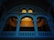 An architectural interior featuring an ornate balcony with curved archways and decorative columns. A chandelier is hanging from the ceiling in the background, casting a warm light that contrasts with the cool blue tone of the structure. The design elements suggest a classical style.