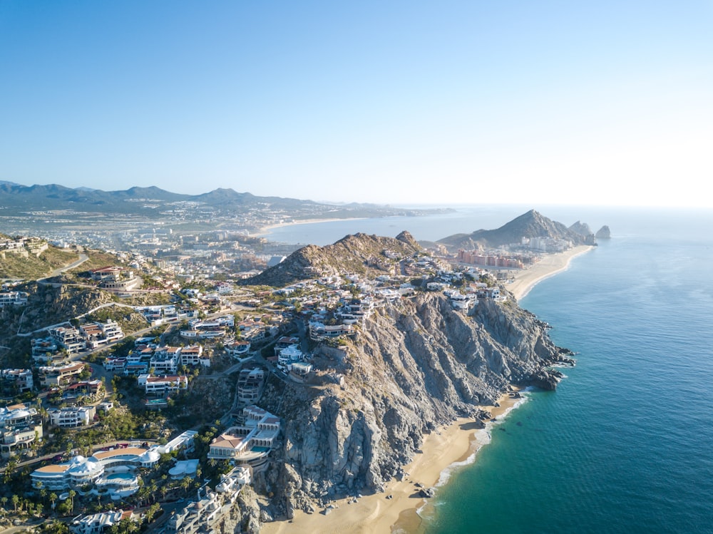 fotografia aérea da montanha com aldeia perto do mar