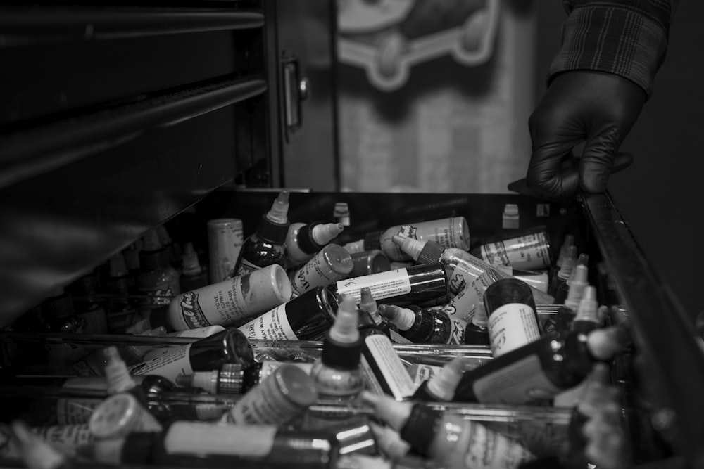 grayscale photography of drawer full of bottles