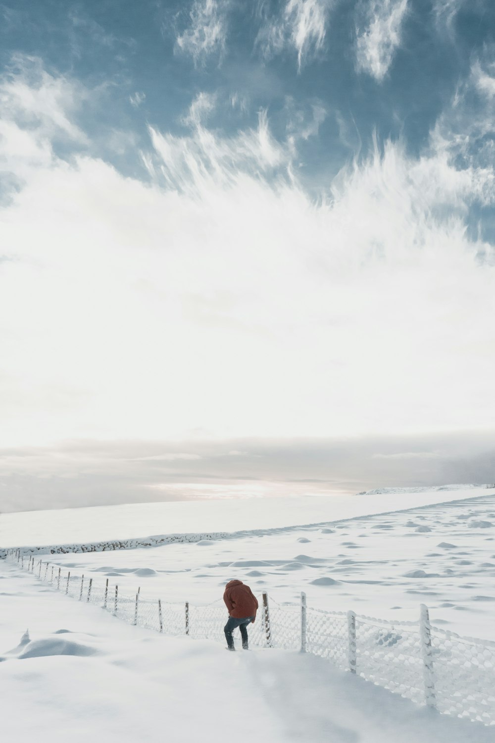 man beside white fence on snowfield