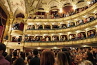 Audience members applauding enthusiastically in a cozy theater