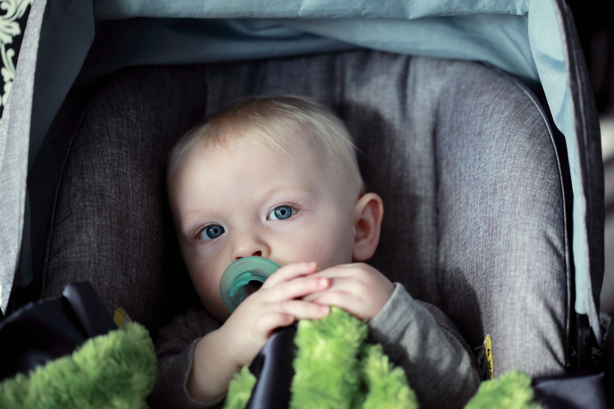 A photo of a one year old baby sitting in his car safety seat. This is our grandson. I shot this using available natural light from a south facing window.