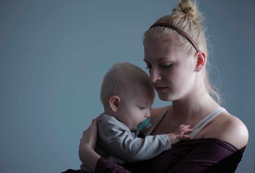 woman carrying baby with pacifier in mouth