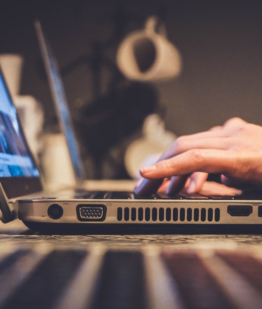 person using silver laptop computer on desk