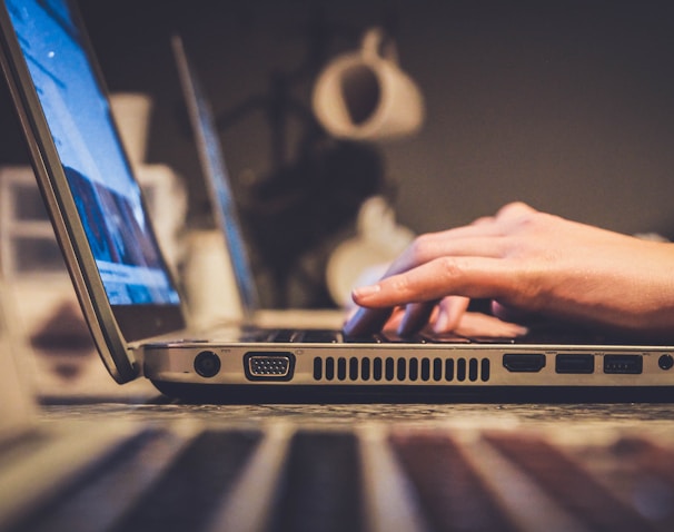 person using silver laptop computer on desk