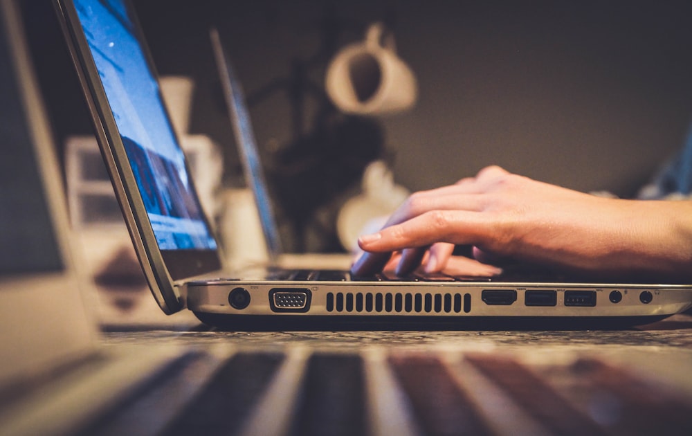 personne utilisant un ordinateur portable argenté sur un bureau