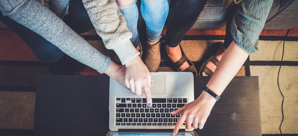 three person pointing the silver laptop computer