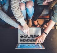 three person pointing the silver laptop computer