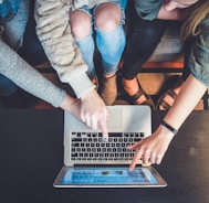 three person pointing the silver laptop computer