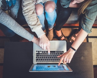 three person pointing the silver laptop computer