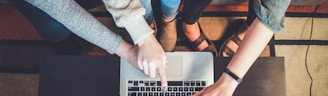 three person pointing the silver laptop computer